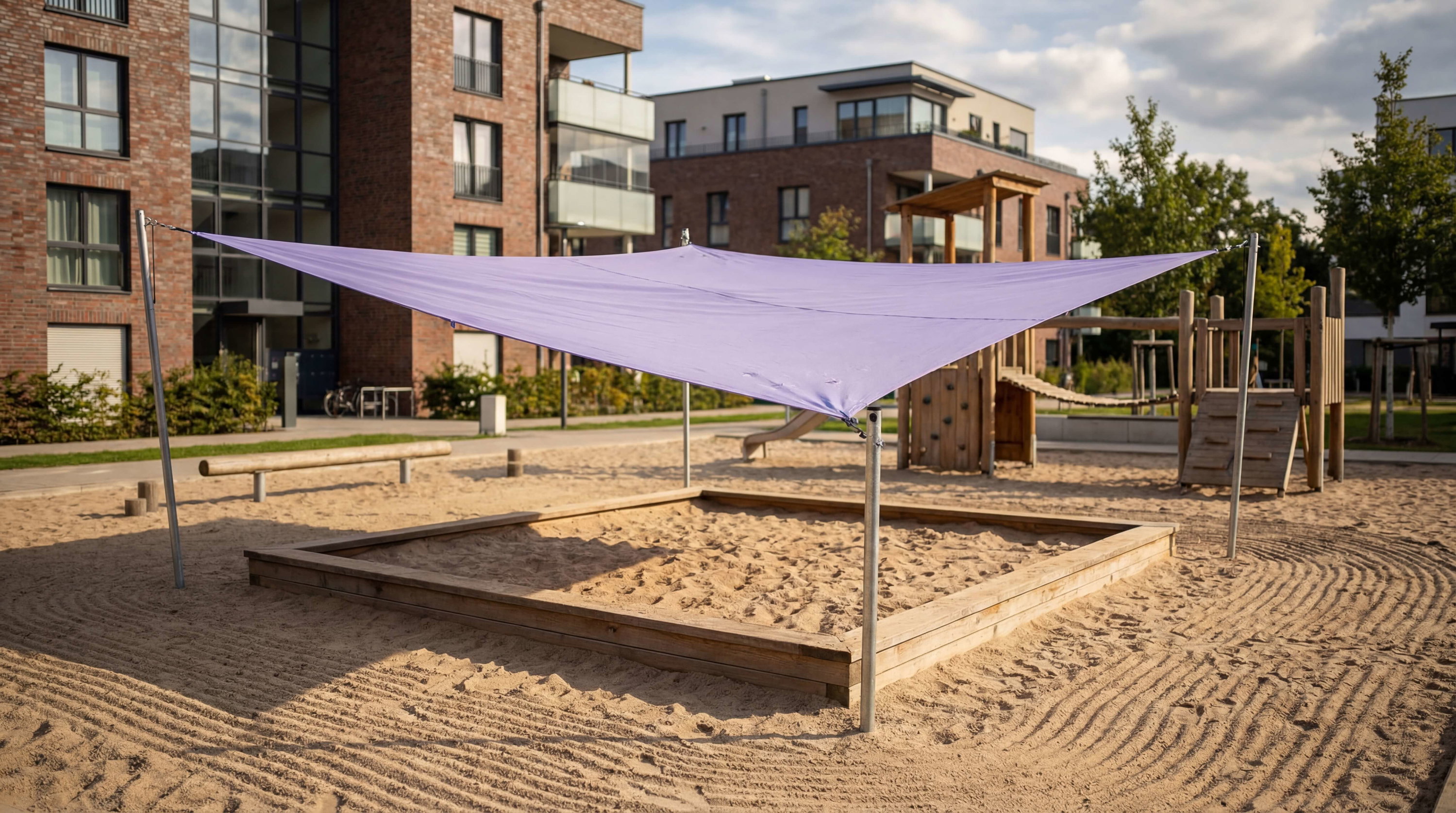 Lila Sonnenschutz über Sandkasten und Spielplatz im Wohngebiet bei sonnigem Wetter.