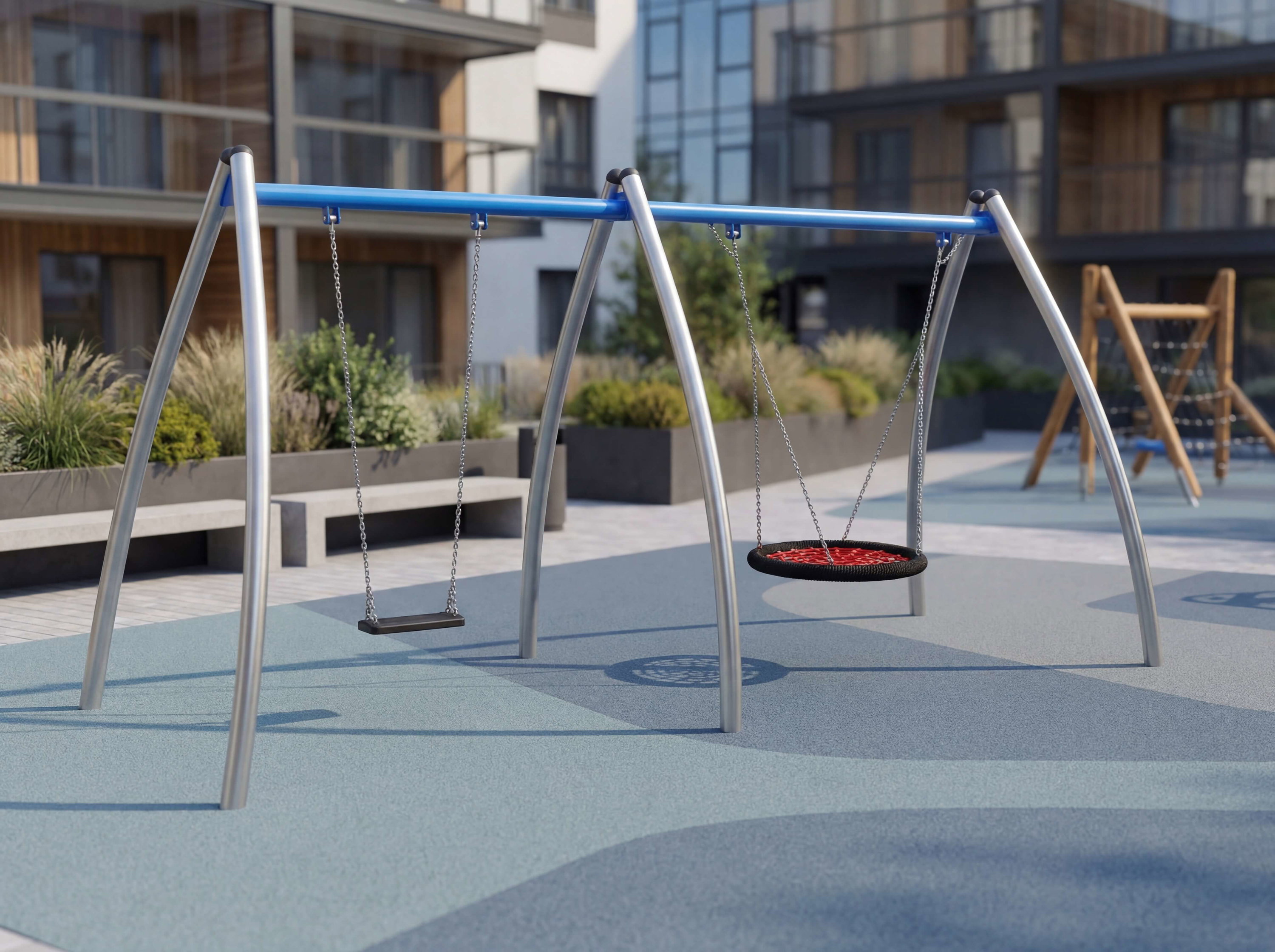 Zwei Schaukeln im modernen Spielplatz vor Wohnhäusern mit blauer Bodenmatte.