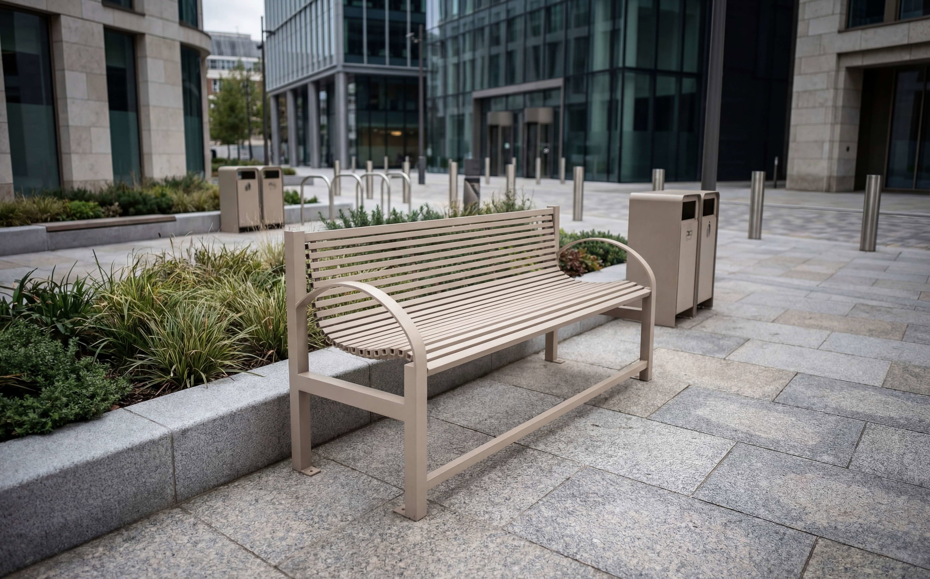 Moderne Bank im urbanen Außenbereich vor Glasfassaden und Pflanzenbeeten.