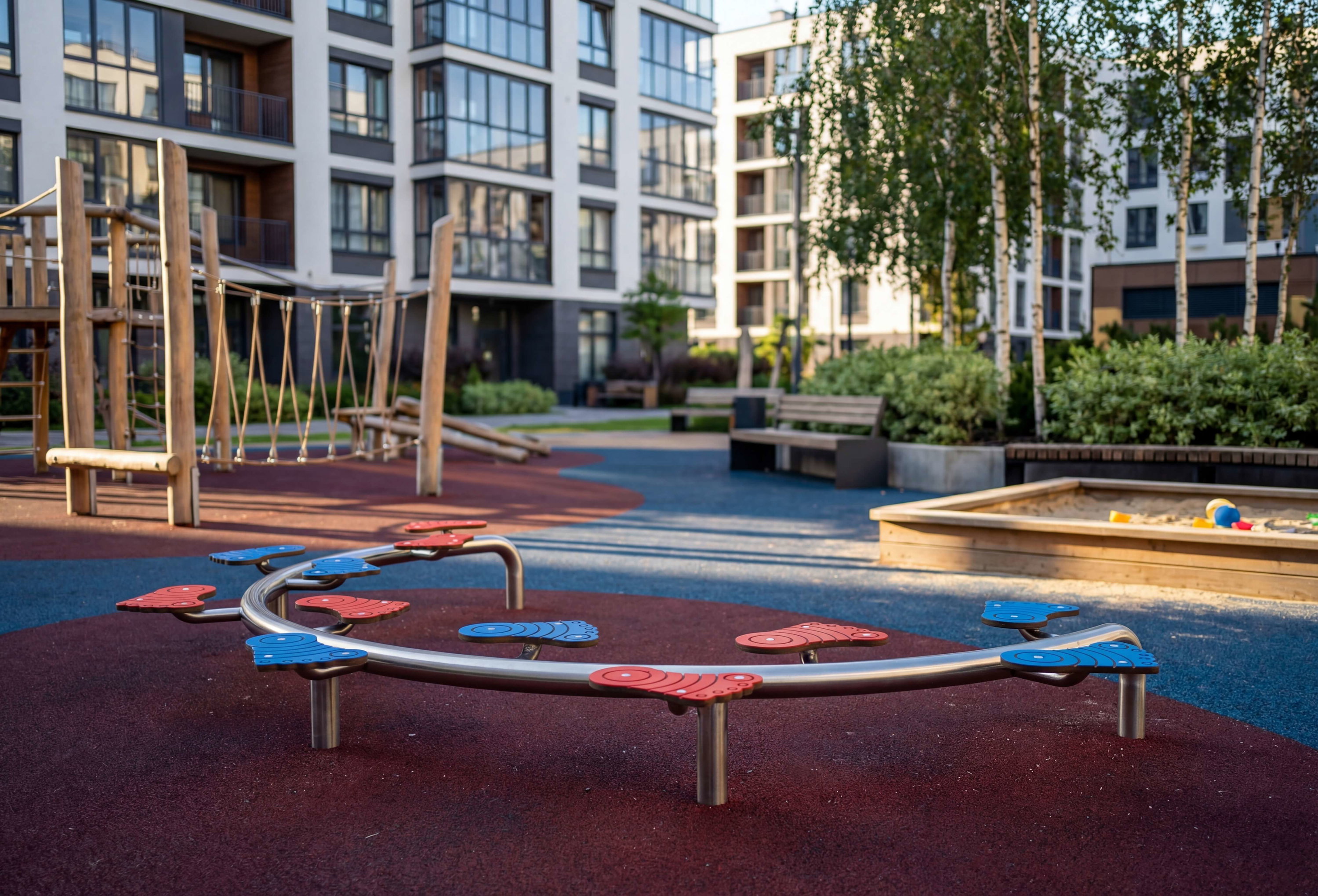 Modern playground with colorful equipment in front of apartment buildings.