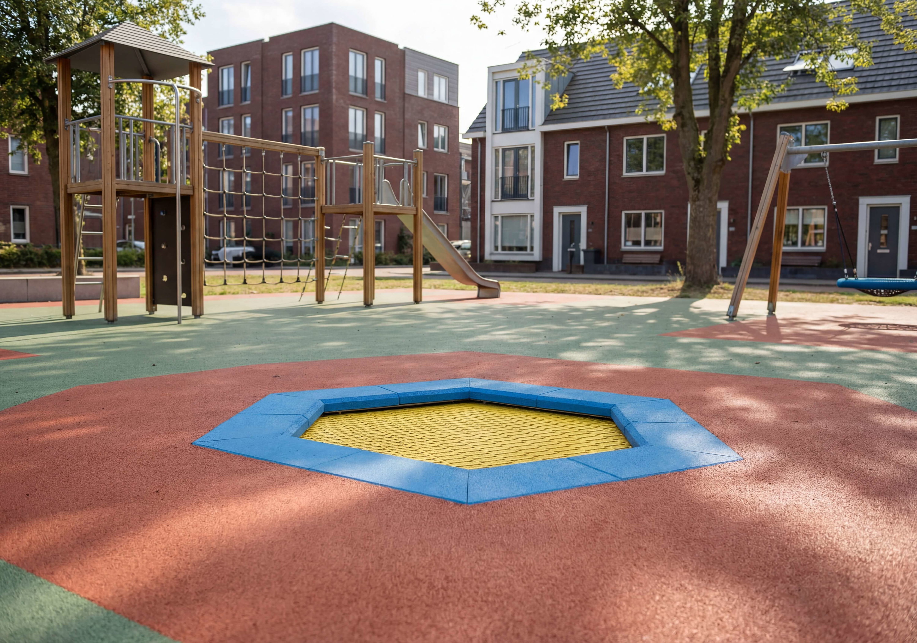 Spielplatz mit Klettergerüst und Rutsche vor Wohnhäusern im Sonnenlicht.
