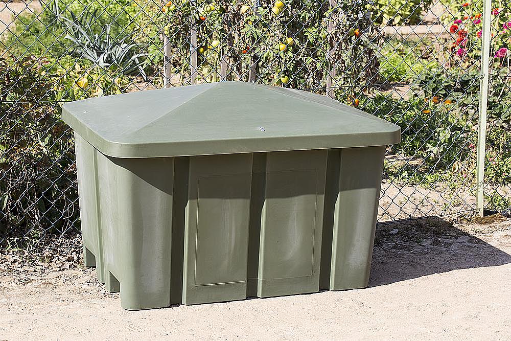 Grunderde Box im Garten hinter Zaun mit Obstbäumen und Blumen.