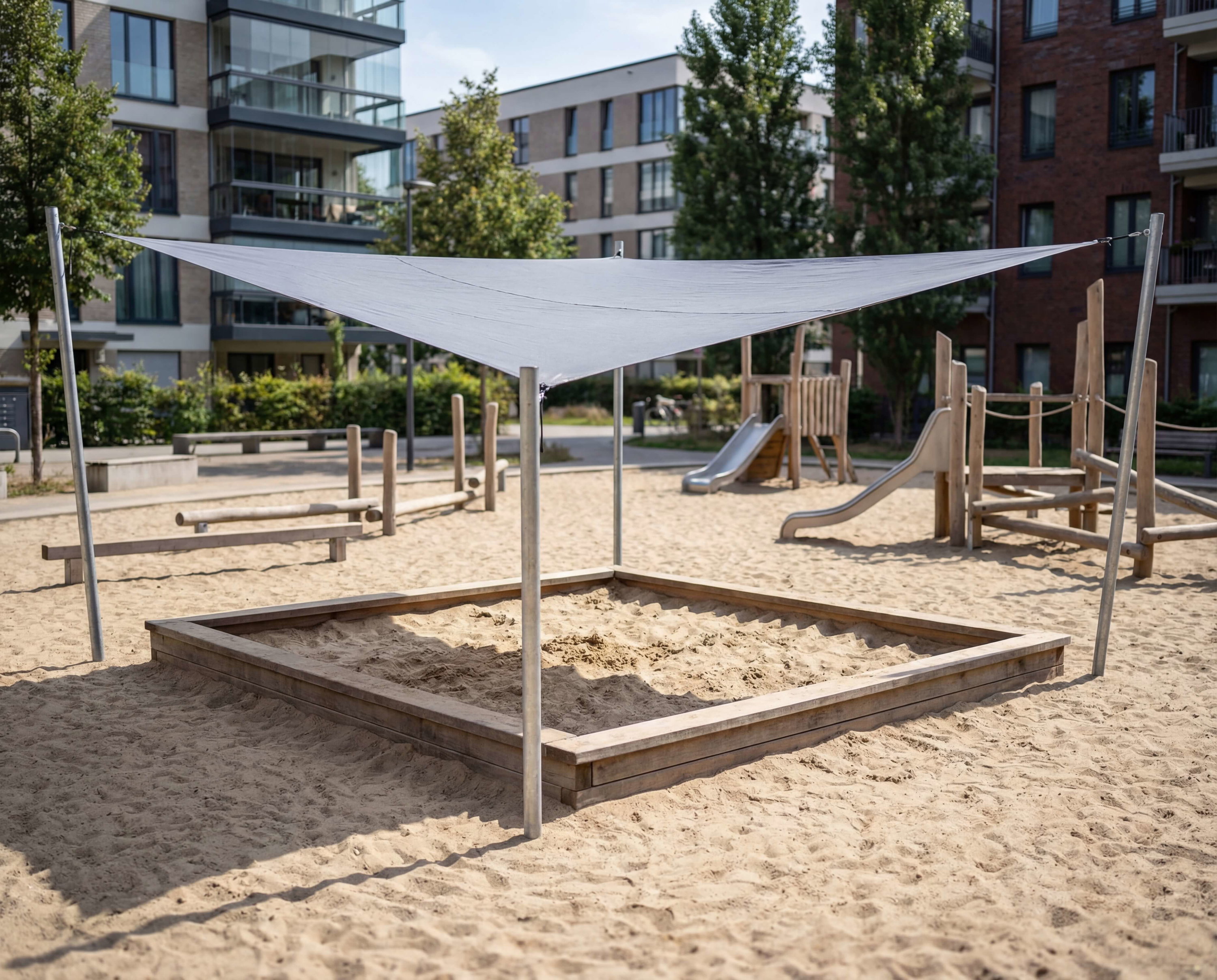 Spielplatz mit Sandkasten und Schattenplane im Wohngebiet – kinderfreundlich und modern gestaltet.