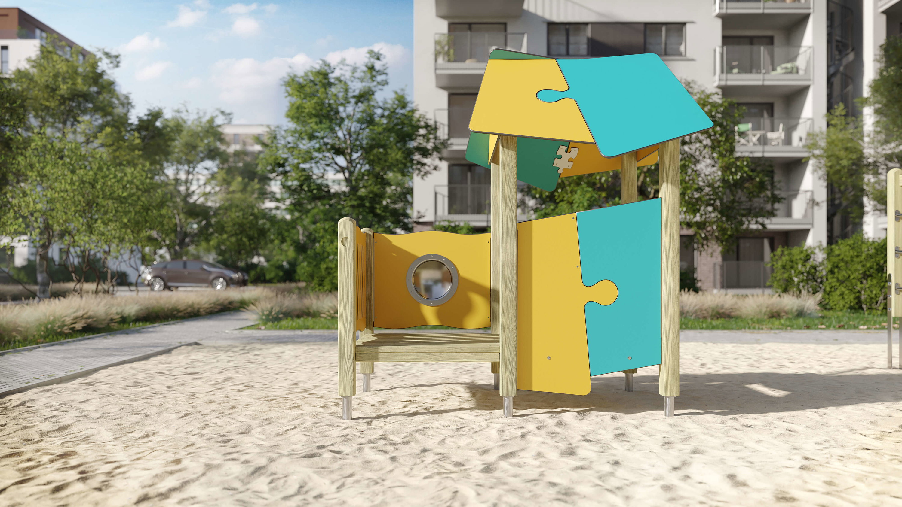 Bunte Spielhütte im Sand auf einem modernen Wohnplatz mit Bäumen und Gebäuden im Hintergrund.
