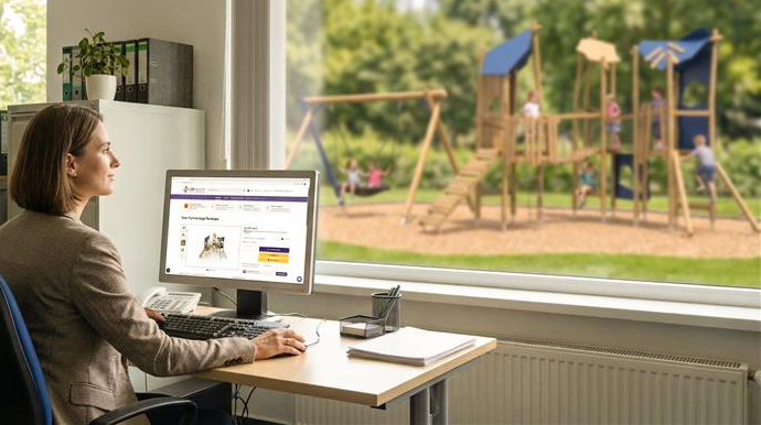 Frau sitzt am Schreibtisch mit Blick aus dem Fenster auf einen Spielplatz