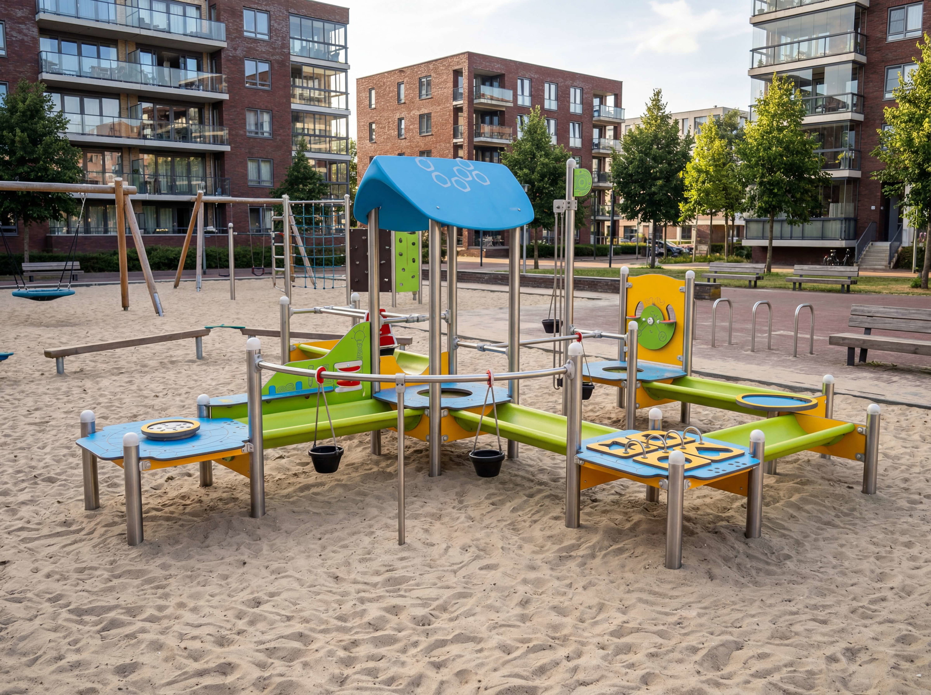 Bunte Spielanlage im Sand mit modernen Hochhäusern im Hintergrund.