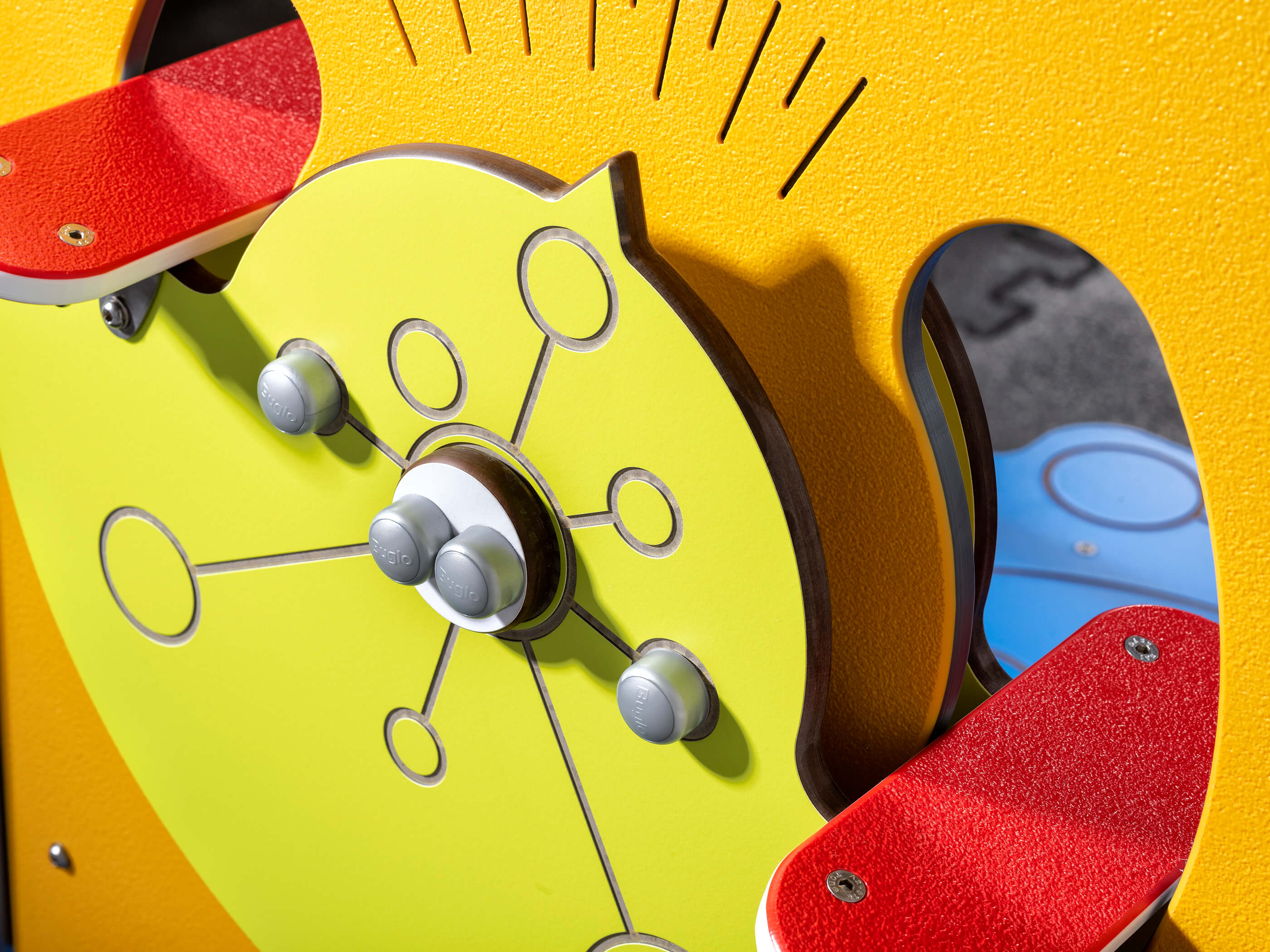 Bunte Spieluhr mit Knöpfen und roten Sitzplätzen für Kinder auf einem gelben Spielplatz.

German:  
Farbige Kinderspieluhr mit Knopfbedienung und rotem Sitz – ideal für den Freizeitpark.