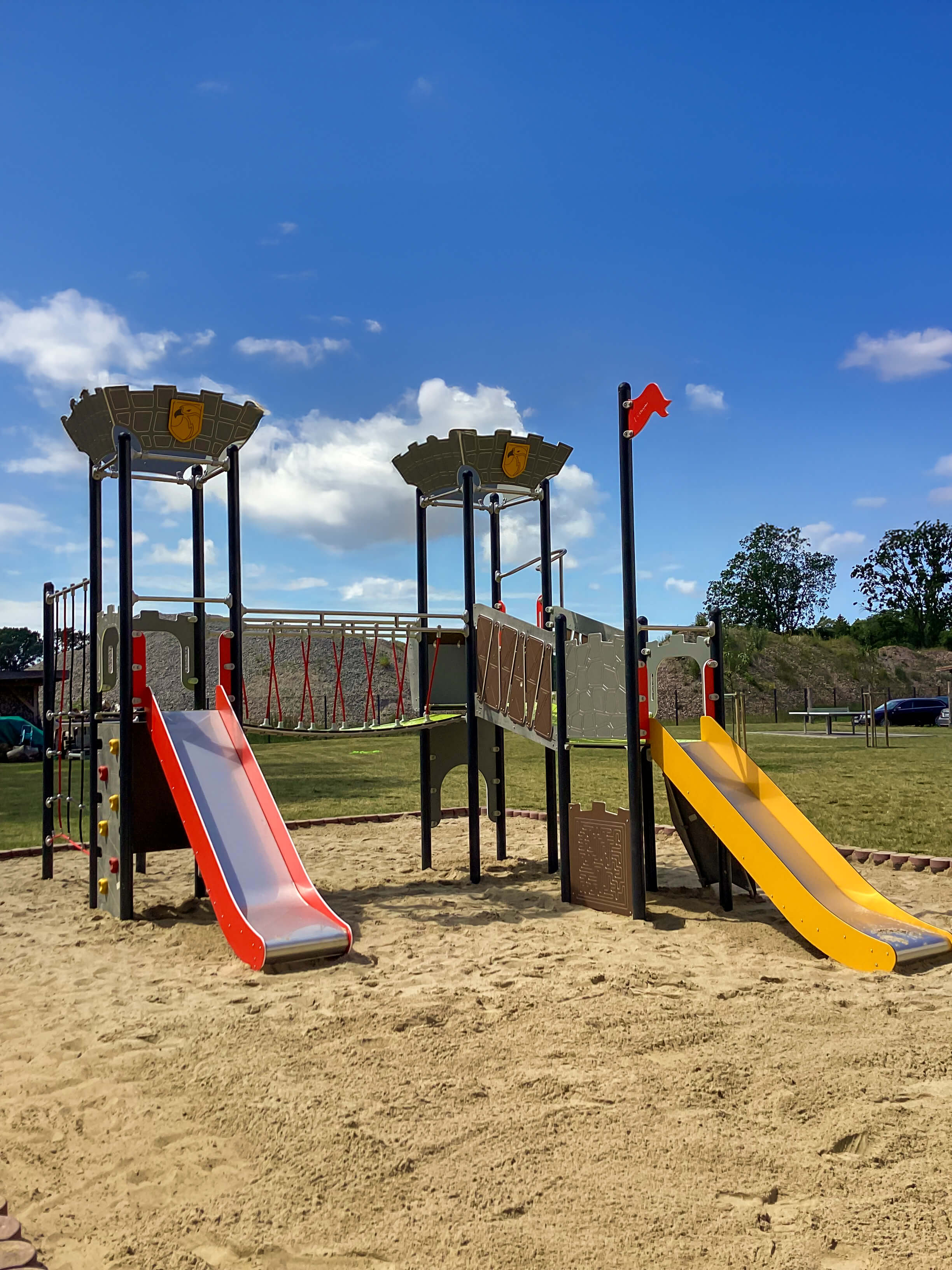 Farbe Spielplatz mit Rutschen und Sandkasten unter blauem Himmel.