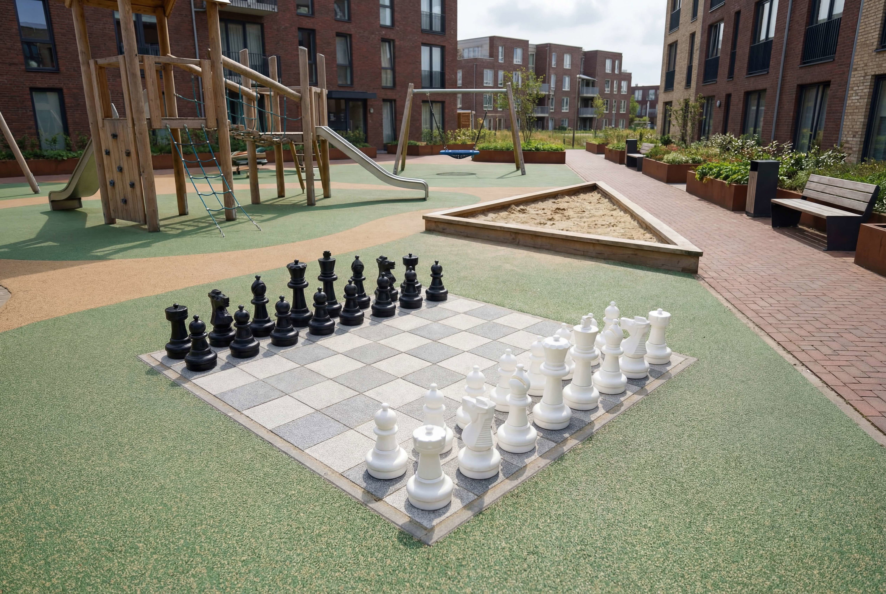 Großes Schachspiel im Spielplatz vor Wohnhäusern – kinderfreundlich und urban gestaltet.