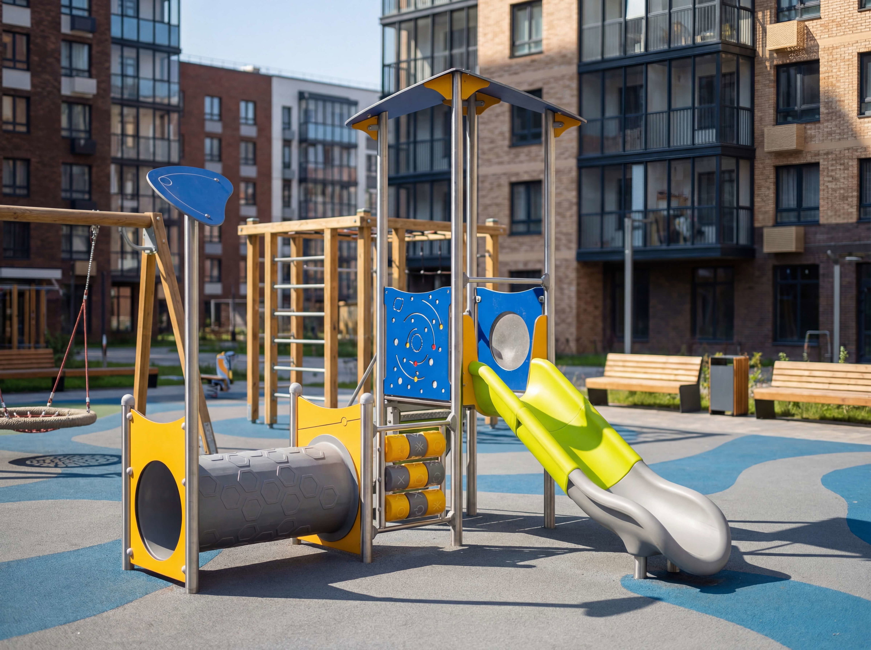 Farbechter Spielplatz mit Rutsche und Tunnel vor modernen Wohnhäusern im Sonnenlicht.