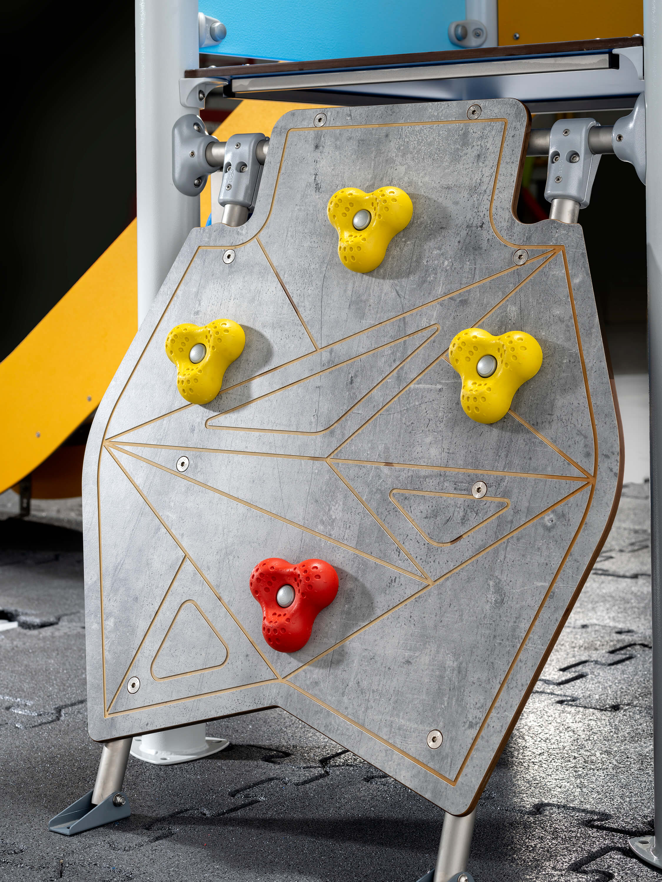 Kletterwand mit gelben und roten Griffen für Kinder im Spielbereich.