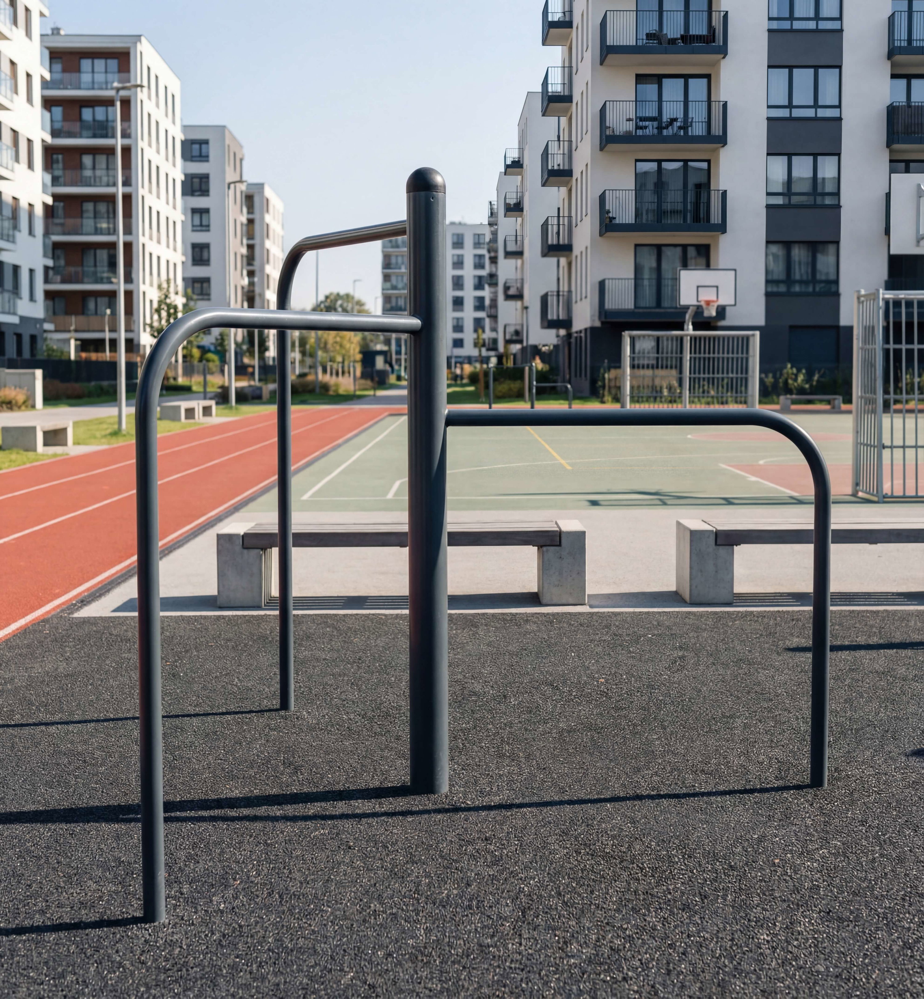 Outdoor fitness station with benches near running track and basketball court in modern residential area.