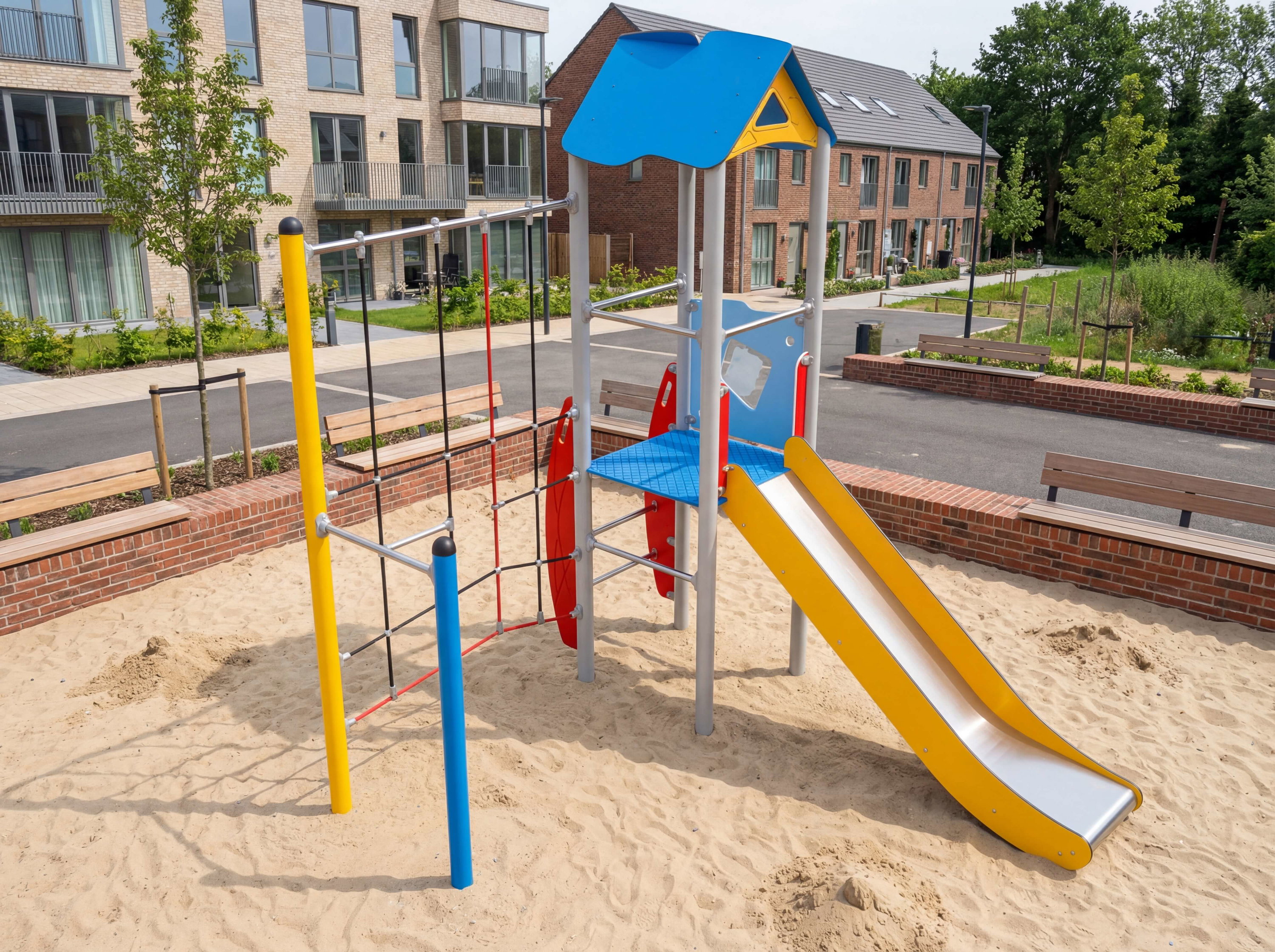Bunte Spielanlage mit Rutsche und Klettergerüst im Sandkasten vor Wohnhäusern.